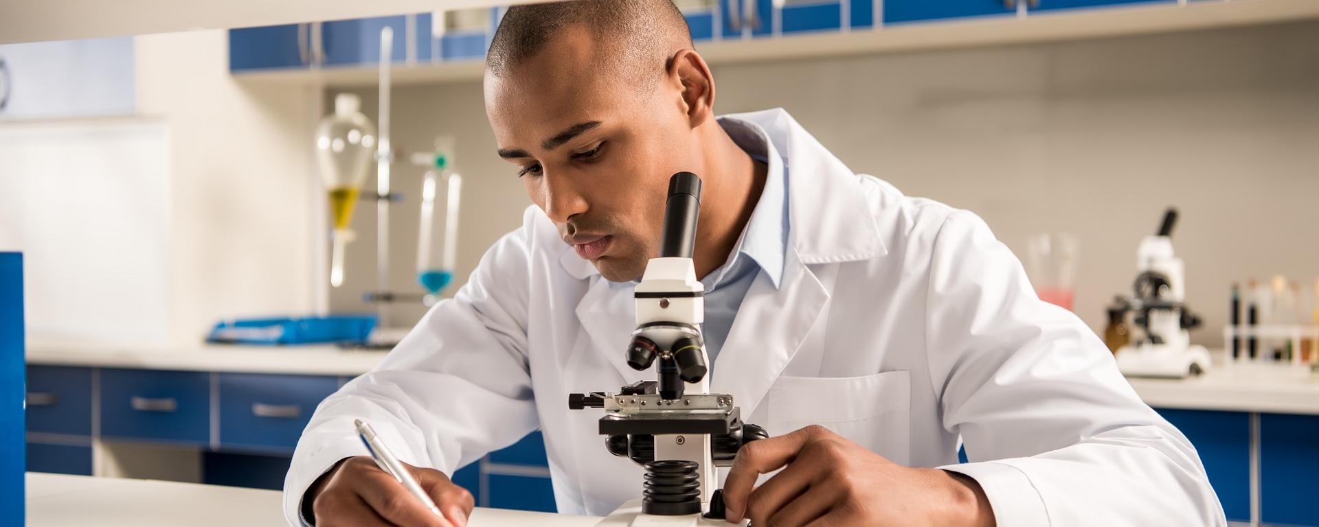 young man in a lab next to microscope