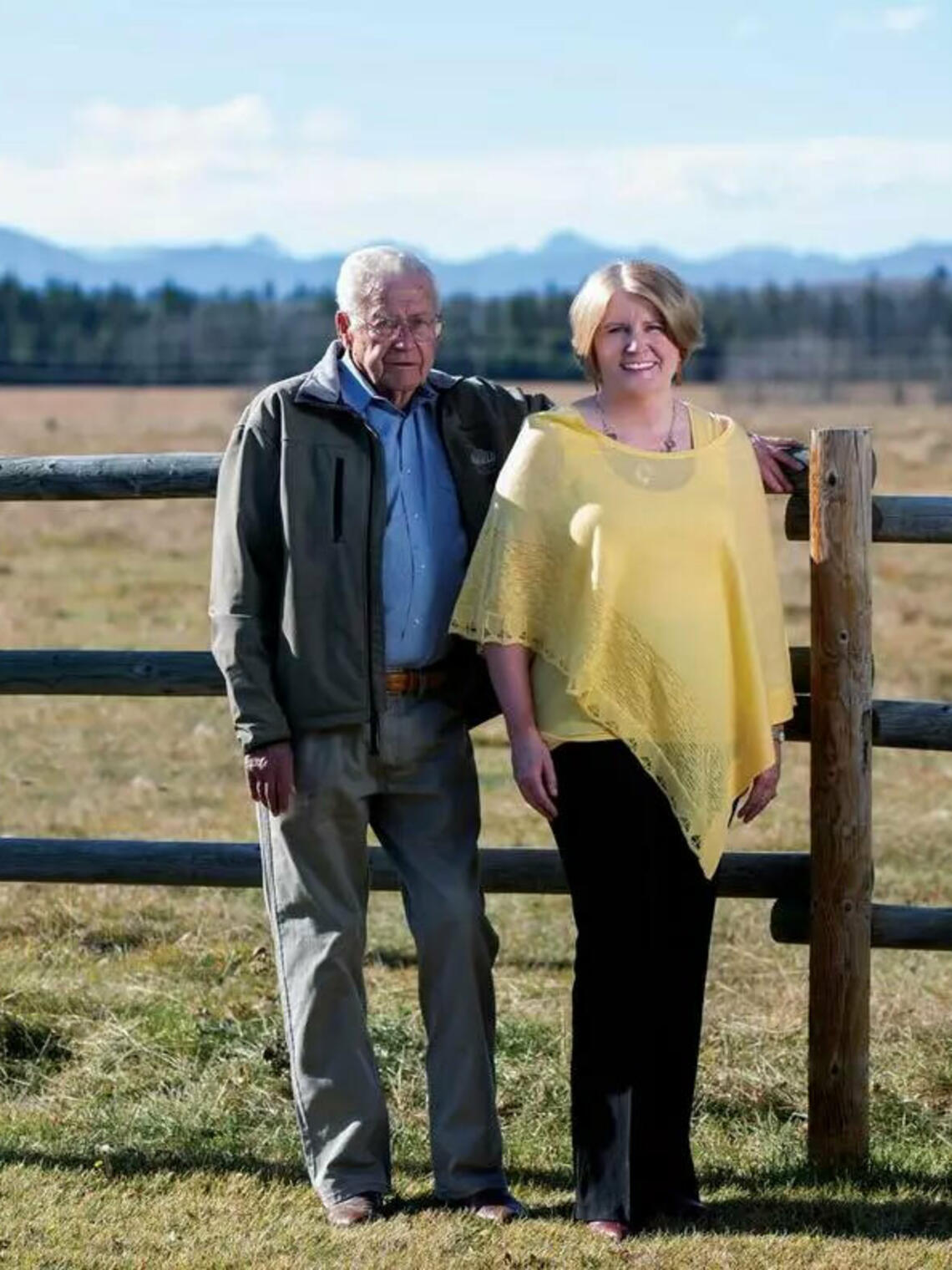 man and woman standing by a fence on a cattle ranch