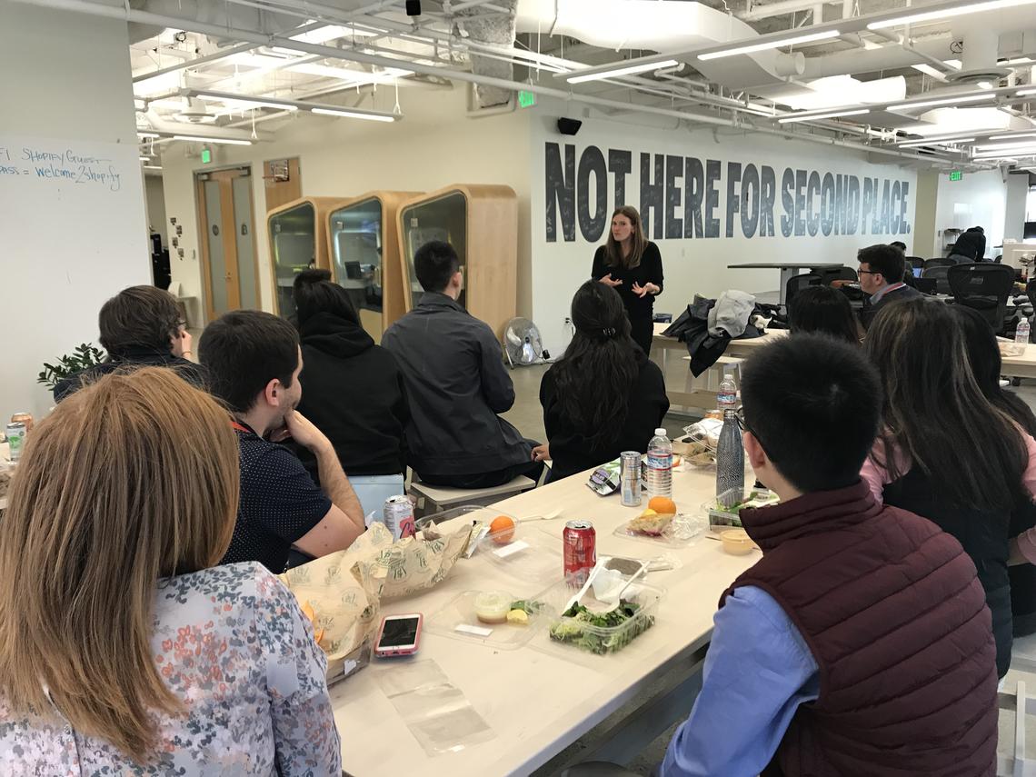 Tour participants visit the offices of Shopify Kit, featuring a sign that reads "not here for second place."