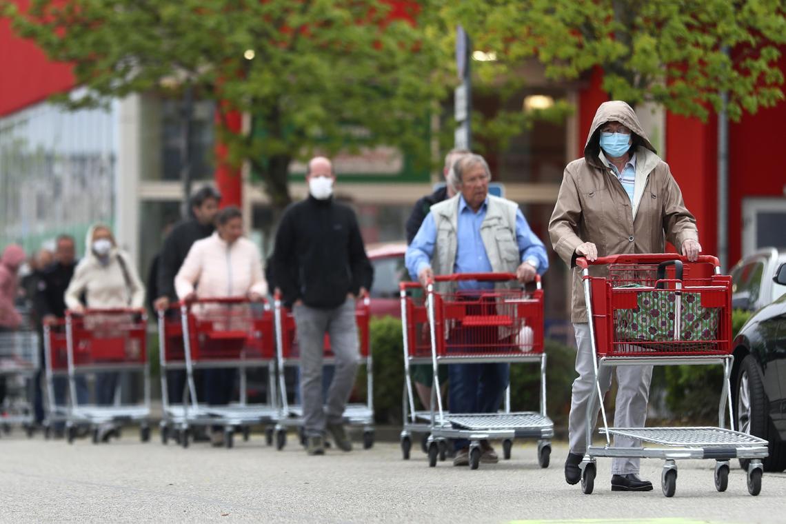 People wearing protective masks queue up to go in a garden store in Munich, Germany on April 20, 2020