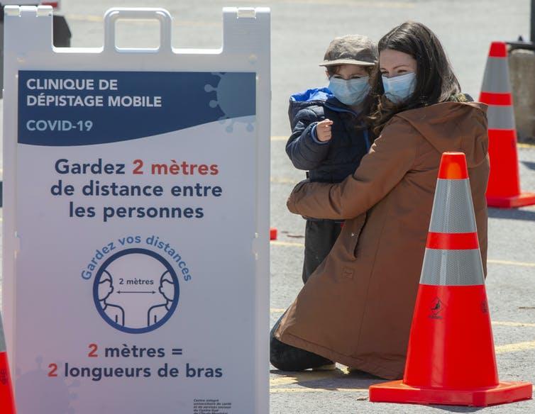 A woman and child wait in line at a mobile COVID-19 testing clinic on May 12, 2020, in Montréal. 