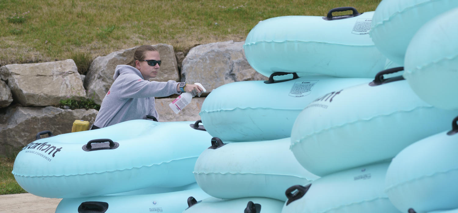 A lifeguard disinfects mattresses used to slide down a water slide in Bromont, Que., in June 2020 as water parks reopened in the province.