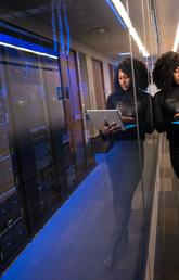 University student looking at laptop standing outside large computer room. 