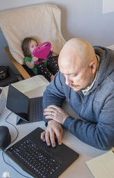 Dad works while toddler does online-preschool, twins adjust to home-kindergarten and mom, on a break, takes the photo. 