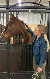 Nicole Phillips pets a horse in a stable.