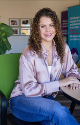 Girl with curly hair in purple shirt and jeans