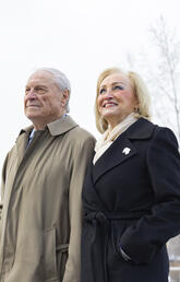 Two people stand side by side outside in the snow