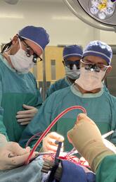 Three people perform surgery