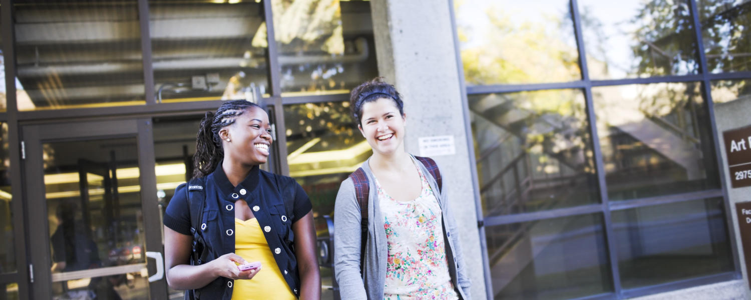 Two women walking outside Mac Hall