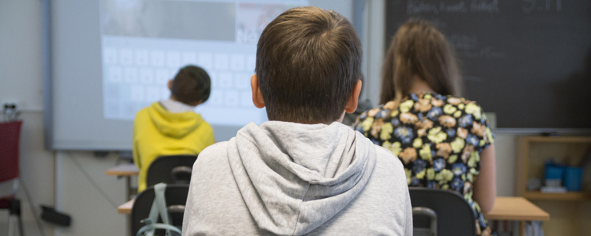 Photo of students in classroom facing screen