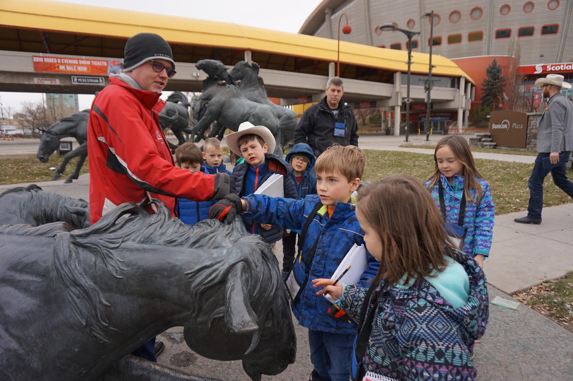 children gather around a teacher and a statue of a bull at Stampede Park