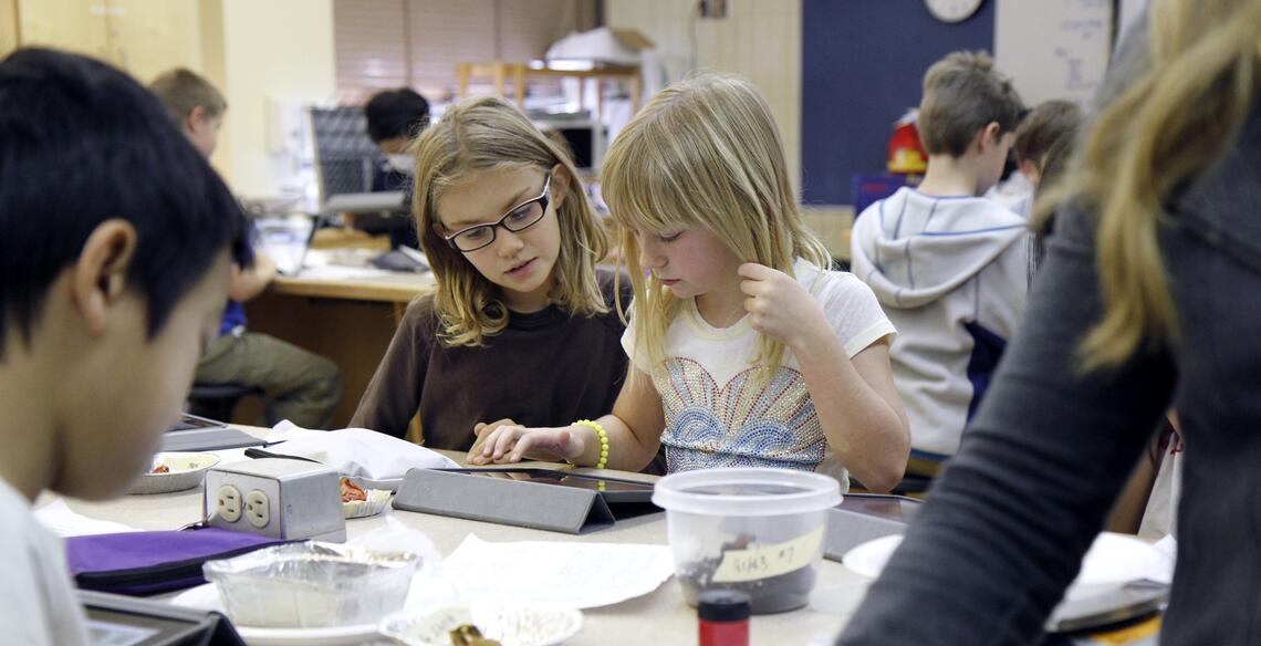 children work on ipads around a desk