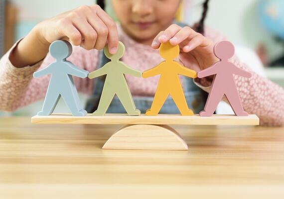 A child balances wooden figures on a fulcrum
