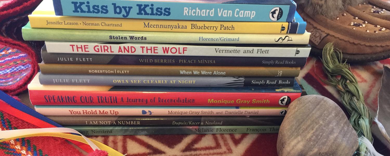 Stack of books surrounded by Indigenous symbols and items